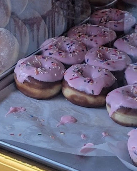 Charola de donas con glaseado rosa y chispas · A tray of pink-glazed sprinkle donuts
